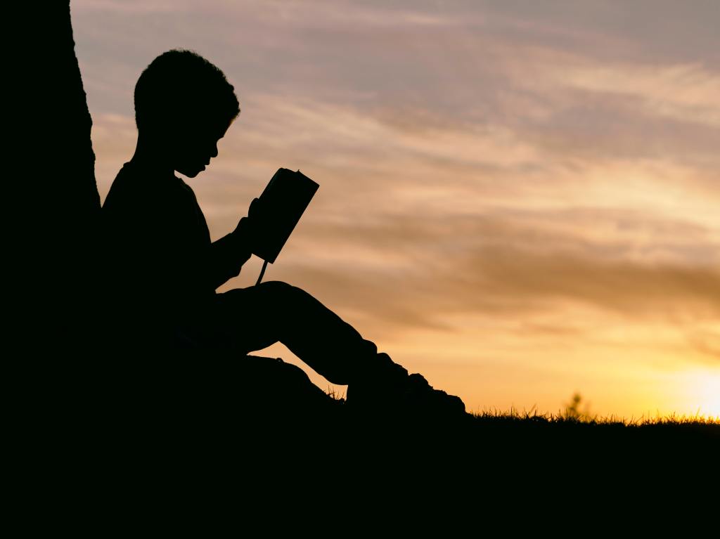 Silhouette of a child reading.